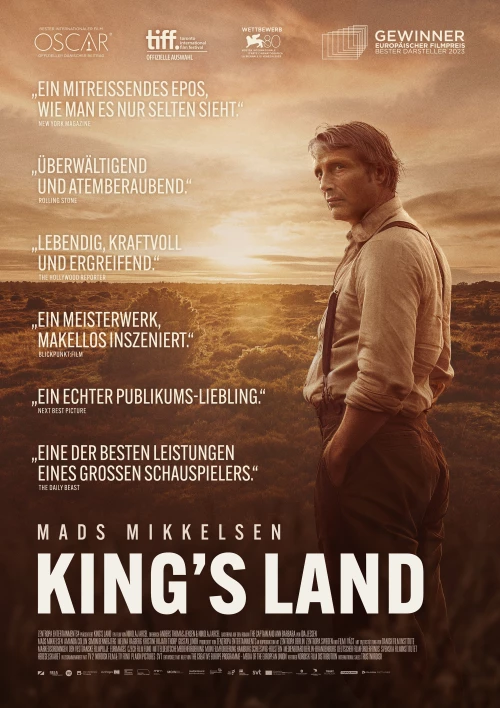 Kinoplakat des Films "King's Land". Hauptdarsteller Mads Mikkelsen steht vor einer weitläufigen Landschaft. Der Sonnenuntergang taucht alles in einen Sepia-Ton. Mit den Händen in den Hosentaschen blickt er mit ernstem Gesichtsausdruck in die Ferne.
