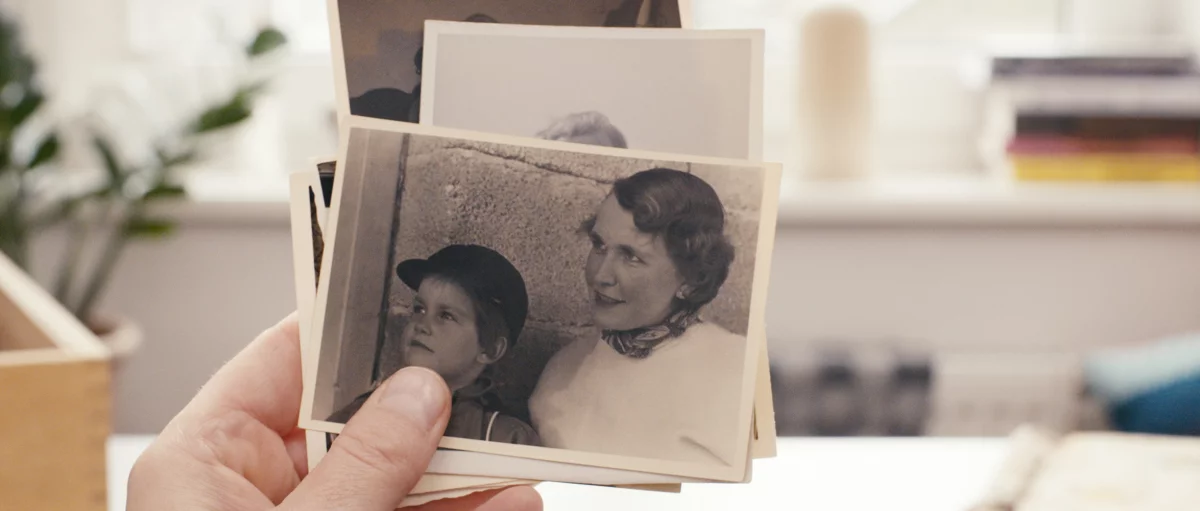 Filmstill "Reproduktion", schwarz-weiß Fotos werden in einer Hand gehalten